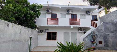 a white building with red windows and a fence at Casa en Mahahual cerca de la playa D2 in Mahahual