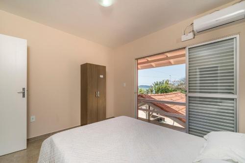 1 dormitorio con cama y ventana con vistas en Aluguel Casa 3 quartos s/ 1 suíte frente Mar | Bombas/SC, en Bombinhas