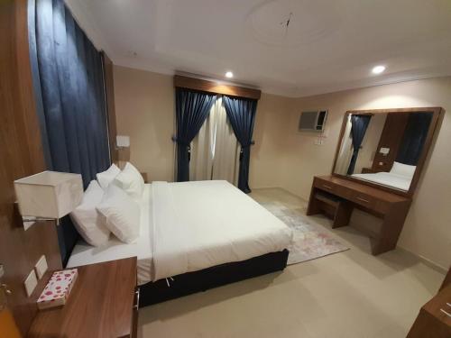 a bedroom with a bed and a desk and a mirror at واحة طيبة للشقق الفندقية in Al Madinah