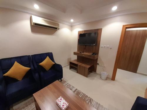 ein Wohnzimmer mit einem blauen Sofa und einem Flachbild-TV in der Unterkunft واحة طيبة للشقق الفندقية in Medina