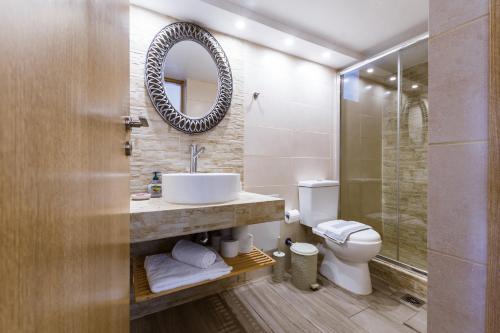 ein Badezimmer mit einem Waschbecken, einem WC und einem Spiegel in der Unterkunft Evelina's House in Platanias