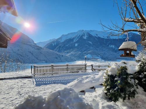 a bench in the snow with mountains in the background at Ferienwohnungen Birkleiten in Bramberg am Wildkogel