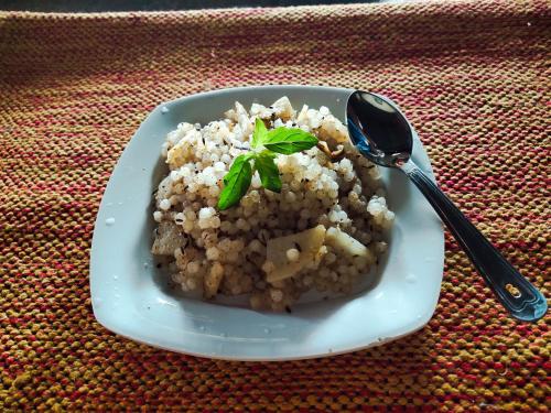 un plato de comida con inoa y una cuchara en una mesa en SiddhaDham - Farm Stay Cottage 1 en Nashik