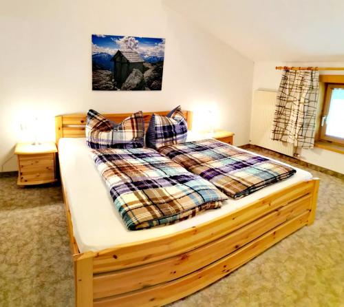 a bedroom with a wooden bed with plaid pillows at Ferienwohnungen Birkleiten in Bramberg am Wildkogel
