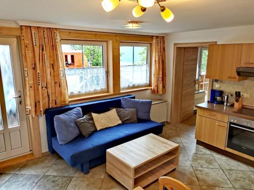 ein Wohnzimmer mit einem blauen Sofa und einem Tisch in der Unterkunft Ferienwohnungen Birkleiten in Bramberg am Wildkogel