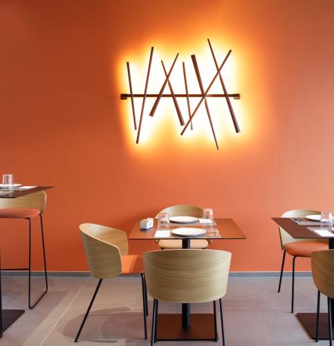 a restaurant with orange walls and tables and chairs at Hotel Cristal in Sirmione