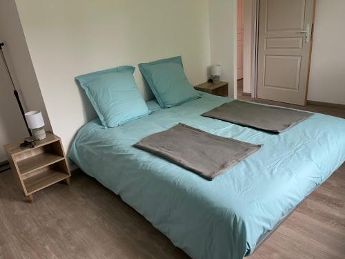 a blue bed with two pillows and a night stand at Le gîte des Vosges II in Fraize