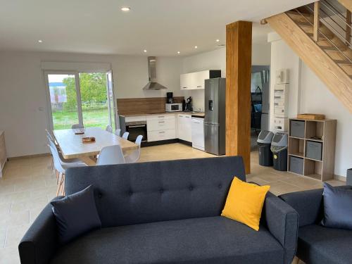 a living room with a blue couch and a kitchen at Le gîte des Vosges II in Fraize