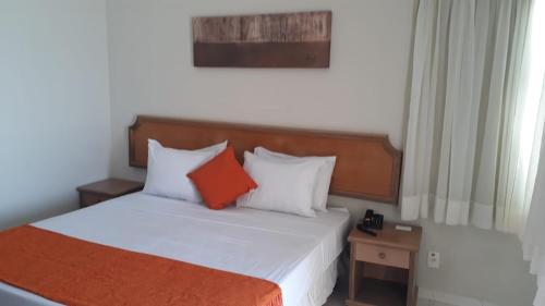 a bedroom with a bed with an orange and white pillow at FLAT COSTA MAR in Recife
