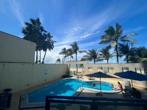 a swimming pool with umbrellas and palm trees at FLAT COSTA MAR in Recife