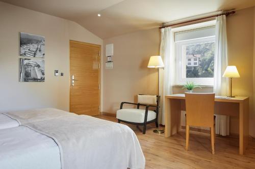 um quarto com uma cama, uma secretária e uma janela em Iraipe Santuario de Arantzazu Hotel em Oñati