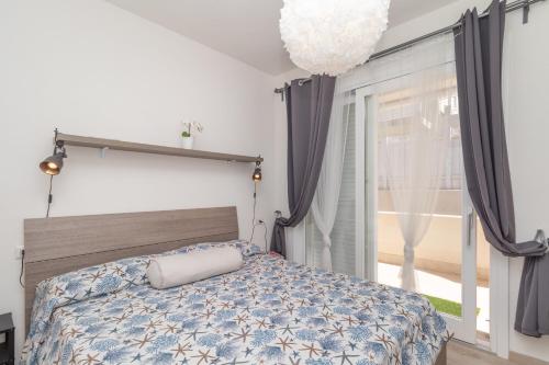 sypialnia z łóżkiem i dużym oknem w obiekcie Stella Marina beach house w mieście Isola Rossa