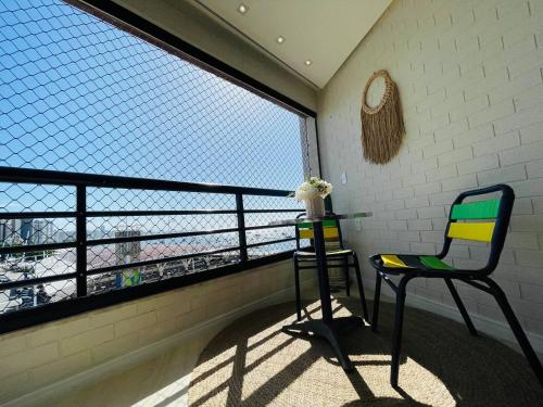uma varanda com 2 cadeiras e uma mesa em frente a uma janela em Flat Luxuoso Alto Padrao Frente Mar com 2 suites no Iate Plaza em Fortaleza