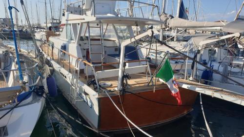 a boat with a flag is docked in a harbor at Salvador BAHIA Boat and Breakfast in Lido di Ostia