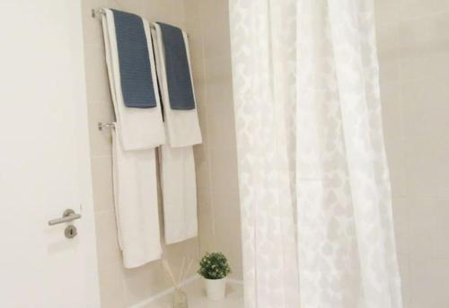 uma casa de banho com toalhas brancas e uma cortina de chuveiro em Cosy flat, Salgados Village em Guia