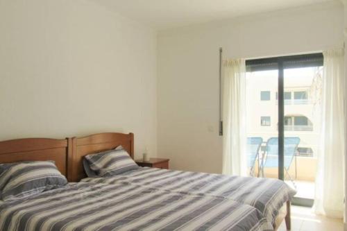 une chambre avec un lit et une porte coulissante en verre dans l'établissement Cosy flat, Salgados Village, à Guia