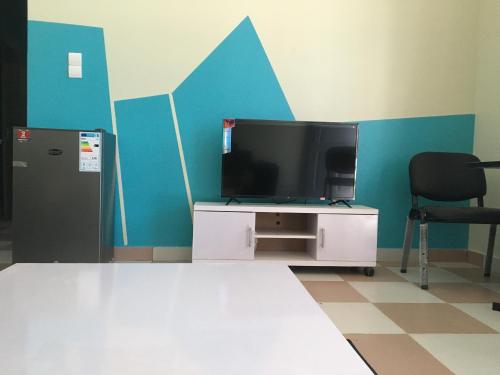 a room with a tv and a desk with a chair at Residence MaryHouse - Free Breakfast and Taxi From Airport in Cotonou