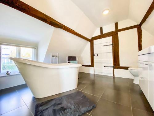 La grande salle de bains est pourvue d'une baignoire blanche et de toilettes. dans l'établissement Mortimer Cottage, à Wootton Rivers
