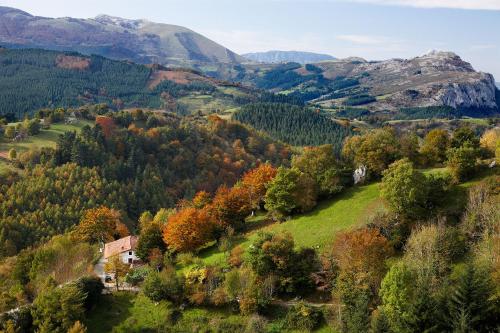 an autumn view of a valley with a house on a hill at Iraipe Santuario de Arantzazu Hotel in Oñate