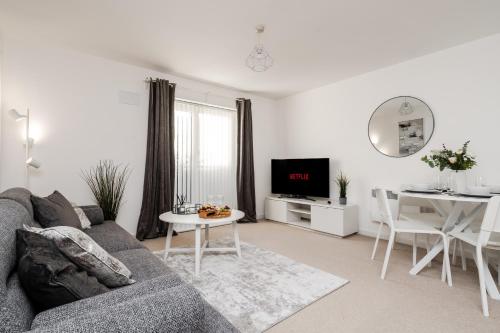 ein Wohnzimmer mit einem grauen Sofa und einem Tisch in der Unterkunft Lovely Modern 2 Bed City Centre Apartment with FREE parking - Double or Twin Beds Available in Wolverhampton