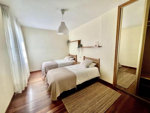 a hotel room with two beds and a mirror at Agradable apartamento céntrico en Cangas in Cangas de Morrazo