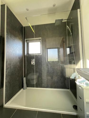 La salle de bains est pourvue d'une douche avec une porte en verre. dans l'établissement Flora's Cliff View, à Kilmuir
