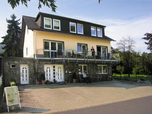 ein großes Haus mit Menschen auf dem Balkon in der Unterkunft Residenz Moselzauber - Ferienwohnungen mit Pool Landschaft in Ernst