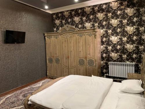 ein Schlafzimmer mit einem großen Bett und einem Kopfteil aus Holz in der Unterkunft TURKISTAN Hotel in Kogon