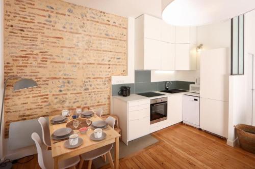une cuisine avec une table en bois et un mur en briques dans l'établissement Confortable T2 à Saint Aubin, à Toulouse