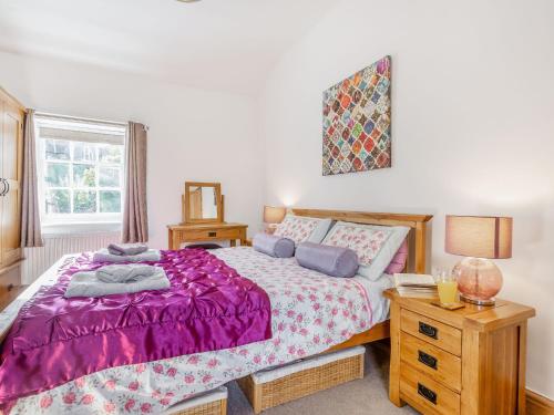 a bedroom with a bed with a purple comforter at Bro Dawel in Dolgellau