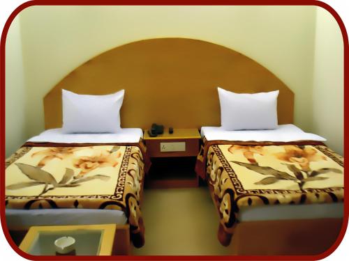 a hotel room with two beds and a table at Hotel de Palazzo in Islamabad