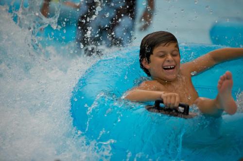 a young boy riding on a blue raft on a water slide at Holiday Inn Resort Jekyll Island by IHG in Jekyll Island