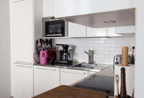 a kitchen with white cabinets and a sink at 2ndhomes Luxury Helsinki Center 2BR Apartment with Sauna in Helsinki