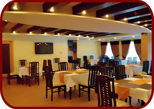 une salle à manger avec des tables et des chaises et une télévision à écran plat dans l'établissement Hotel de Palazzo, à Islamabad