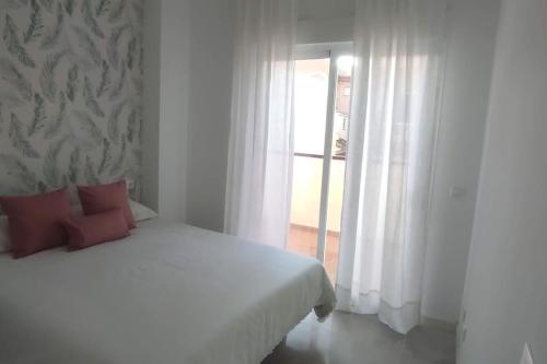 ein weißes Schlafzimmer mit einem Bett und einem Fenster in der Unterkunft Precioso apartamento en el corazon de la cala. in Mijas Costa