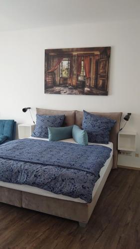 Maxim Apartments Mainz في ماينز: غرفة نوم بسرير وملاءات زرقاء ولوحة على الحائط