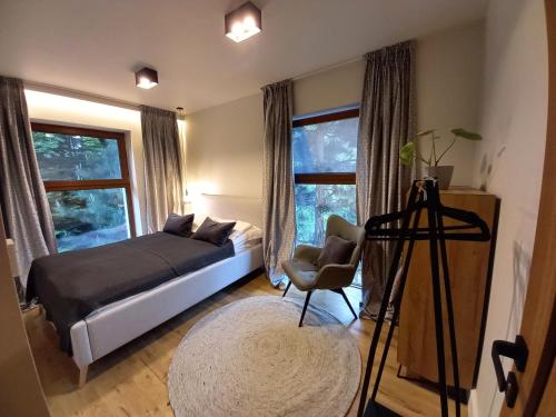 een slaapkamer met een bed, een stoel en ramen bij Dom Winiarza in Krosno