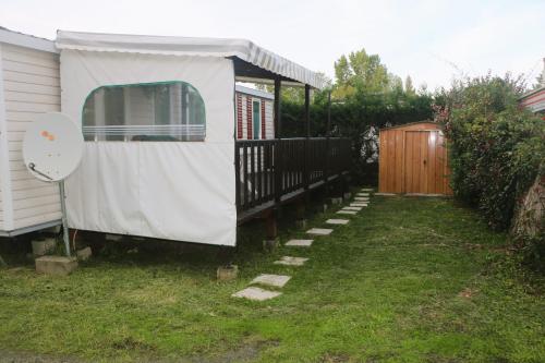 una casa con una tienda al lado de un patio en Mobil-Home 3 chambres à "Les Mathes" en Les Mathes