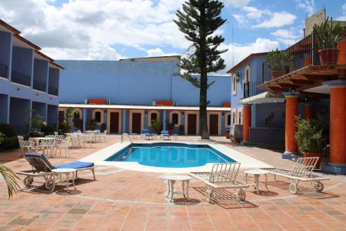 a pool in a courtyard with chairs and a building at Santa Helena Plaza in Oaxaca City