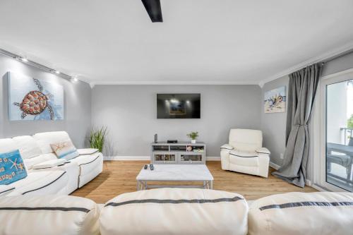 a living room with two white couches and a tv at Holiday Villas 2 104 in Clearwater Beach