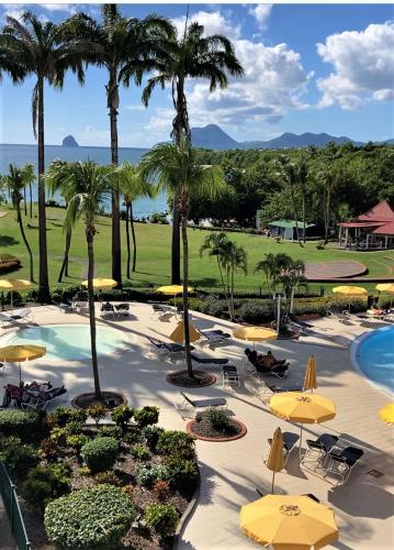 a resort with a pool and chairs and umbrellas at SUPERBE STUDIO MARTINIQUE VUE ROCHER DU DIAMANT in Sainte-Luce