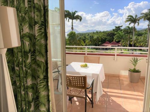 a balcony with a table and chairs and a view at SUPERBE STUDIO MARTINIQUE VUE ROCHER DU DIAMANT in Sainte-Luce