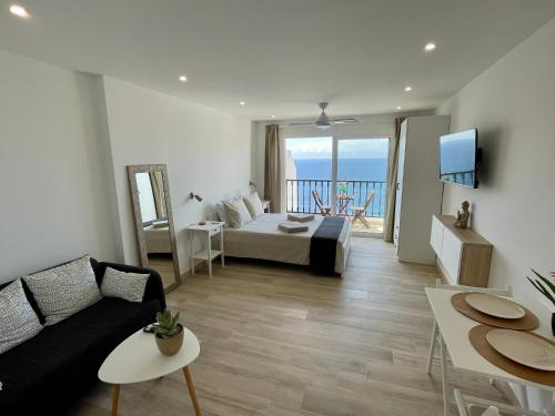 ein Wohnzimmer mit einem Bett und einen Balkon mit Meerblick in der Unterkunft Amazing sea views from cozy studio. in Puerto de Santiago