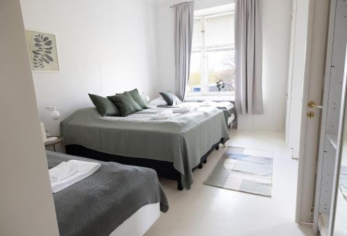 a white room with three beds and a window at 2ndhomes City Center 2BR Apartment with Balcony and Sauna by Kaisaniemi Park in Helsinki