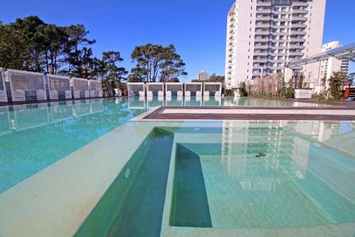 een groot zwembad met blauw en groen water bij Yoo Punta Del Este in Punta del Este