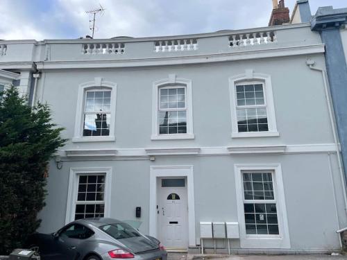 a white house with a car parked in front of it at 3 Bedroom Self Contained Ground Floor Flat With Parking in Plymouth