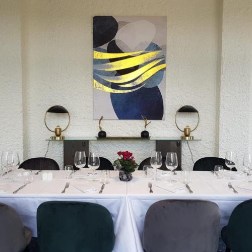 a table with wine glasses and a painting on the wall at Hotel De La Poste in Mortain