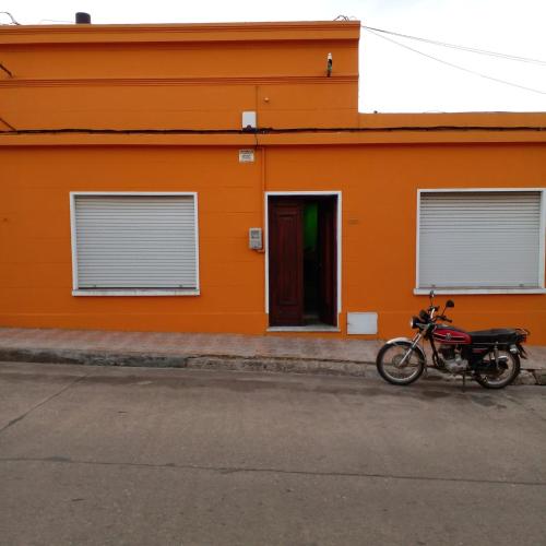 ein Motorrad, das vor einem orangenen Gebäude parkt in der Unterkunft Casa Ituzaingó in Minas