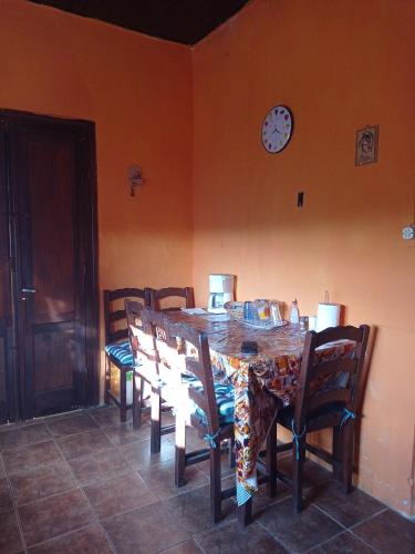 uma mesa de jantar com cadeiras e um relógio na parede em Casa Ituzaingó em Minas