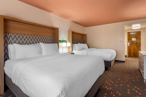two beds in a hotel room with white sheets at Holiday Inn Bangor by IHG in Bangor